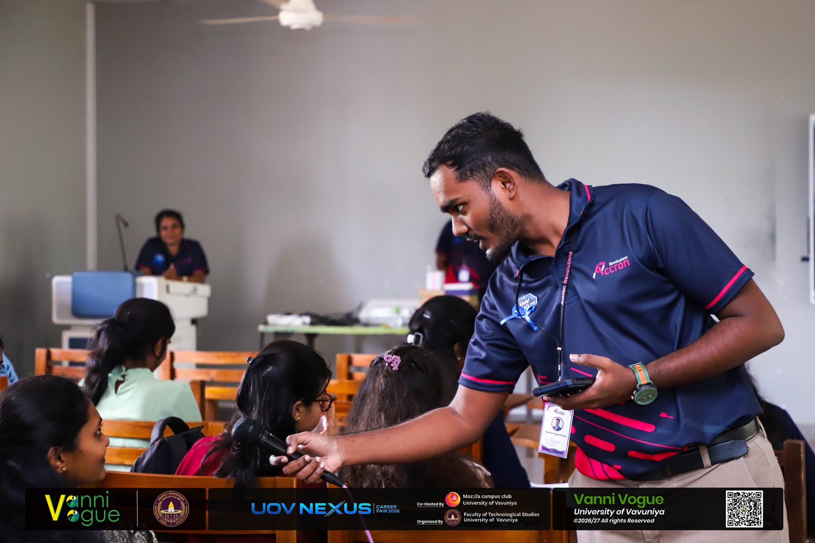 Accron Revolutions team member handing a gift to a student who answered a quiz question at the University of Vavuniya Career Fair session